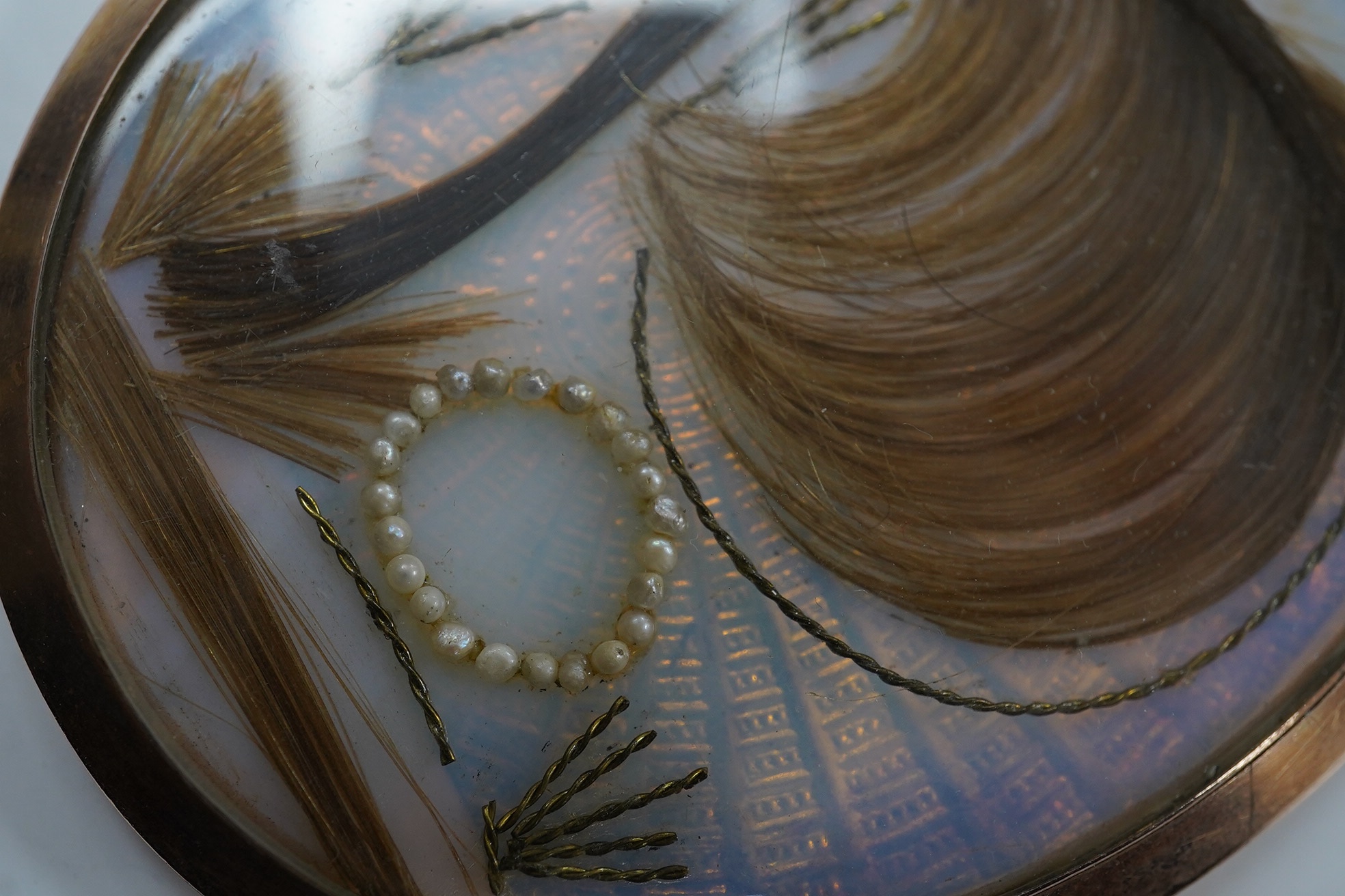 A late 18th century miniature on ivory, Portrait of a lady, initialled NR and dated 1799, lock of hair and seed pearls verso, housed in a yellow metal pendant case, overall 8.2cm x 5.9cm. CITES Submission reference DZHTZ